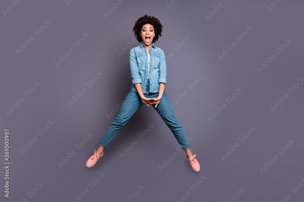 Full length body size photo beautiful she her dark skin excited lady jumping high arms hands together scream shout yell triumphant champion wear casual jeans denim shirt isolated grey background