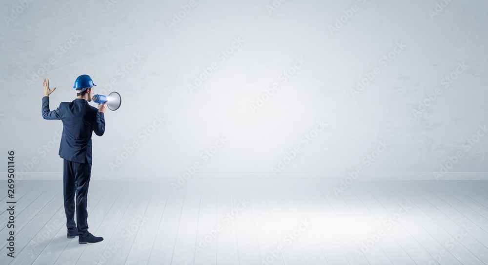 Young architect with construction helmet standing in an empty space and holding a plan
Young architect with construction helmet standing in an empty space and holding a plan