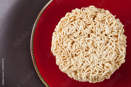 Close up Raw Instant noodles isolated on a red plate with space for copy.