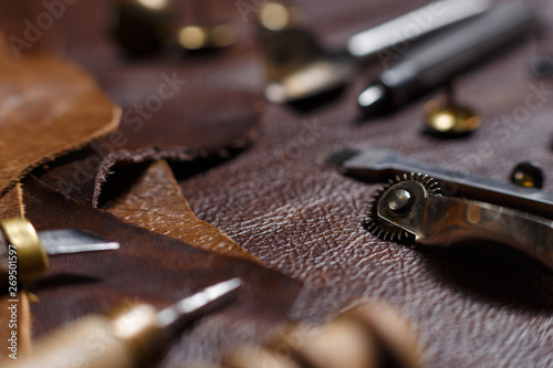 Leather crafting. Leather working tools and pieces of leather in the tailoring workshop. Close-up