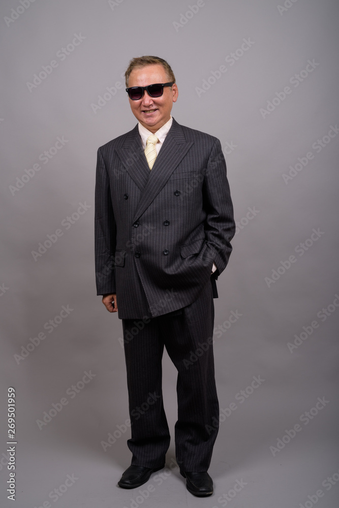 Portrait of mature Asian businessman against gray background Portrait of mature Asian businessman against gray background