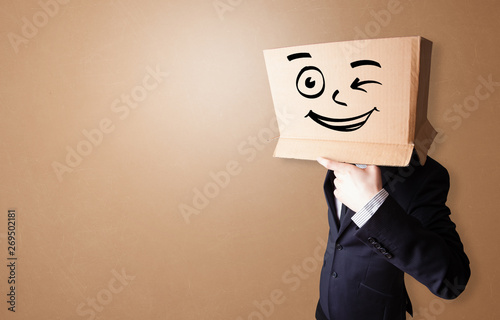 Handsome man standing and gesturing with a carton box on his head 