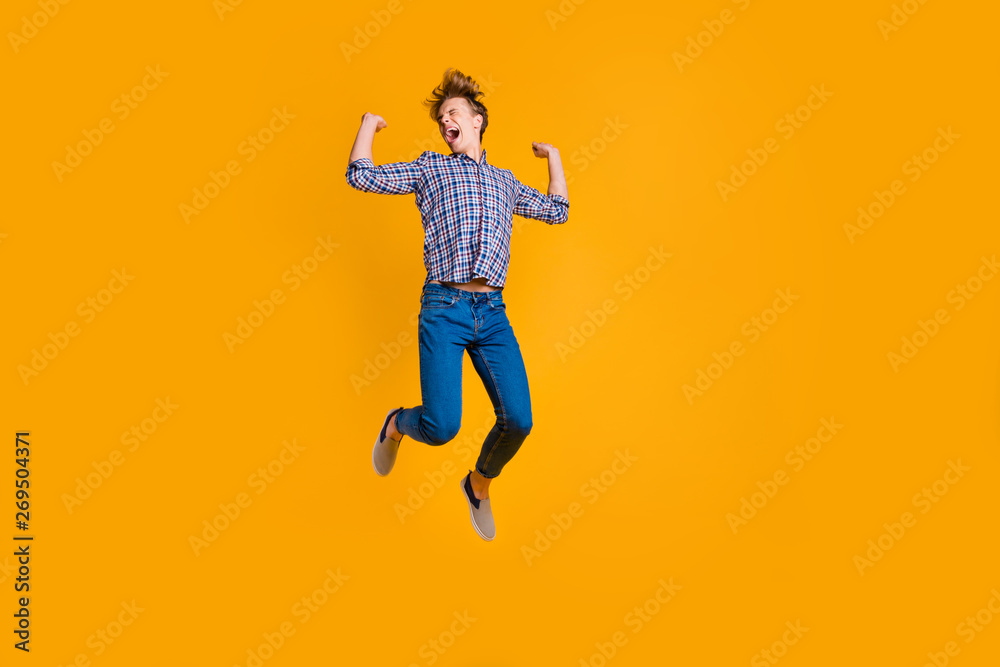 Full length body size view portrait of his he nice attractive cheerful cheery optimistic guy in checked shirt having fun flying isolated over bright vivid shine yellow background Full length body size view portrait of his he nice attractive cheerful cheery optimistic guy in checked shirt having fun flying isolated over bright vivid shine yellow background