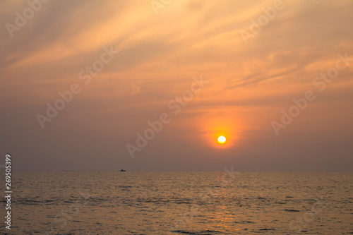 boat in the sea on a background of purple sunset sky with bright yellow sun