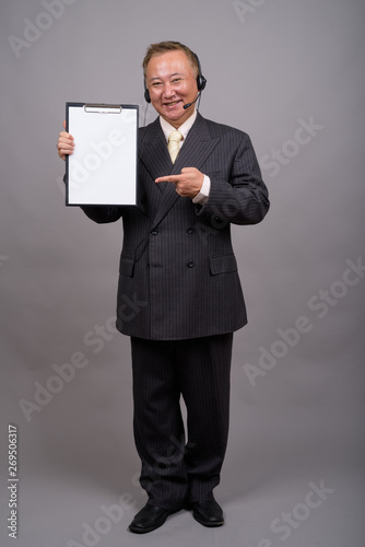 Portrait of mature Asian businessman against gray background