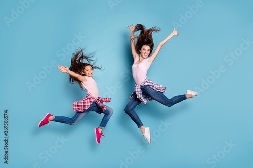 Full length body size view portrait of two nice attractive cheerful careless carefree sportive straight-haired girls having fun hipster look isolated on bright vivid shine blue turquoise background