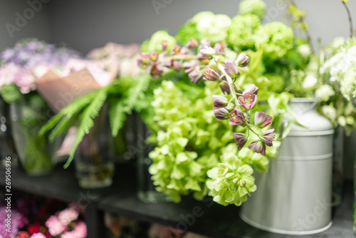 Flower shop concept. Glass vases with different flowers on the shelves of the refrigerator showcases. Abstract background of floral. Flowers composition.