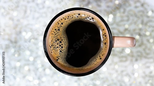 Fragrant black coffee in a cup. Smoke from black hot coffee. Advertising coffee. Glitter lights background. defocused.