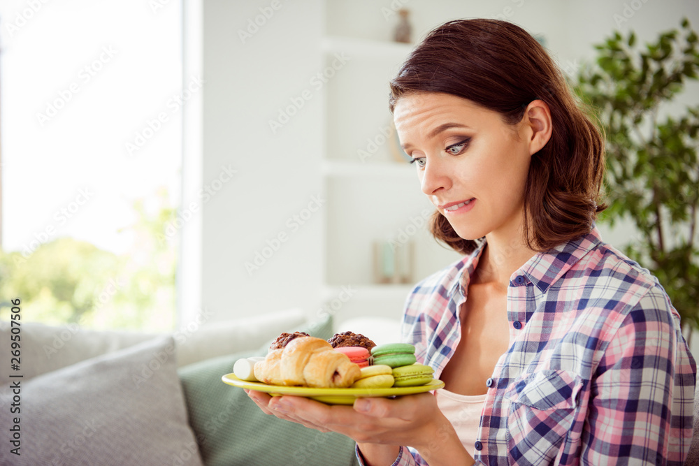 Close up photo of charming funny funky millennial hold hand plate dish pastry confectionery want eat diet difficult dilemma wear checkered shirt modern wavy curly hairstyle hairdo apartment Close up photo of charming funny funky millennial hold hand plate dish pastry confectionery want eat diet difficult dilemma wear checkered shirt modern wavy curly hairstyle hairdo apartment