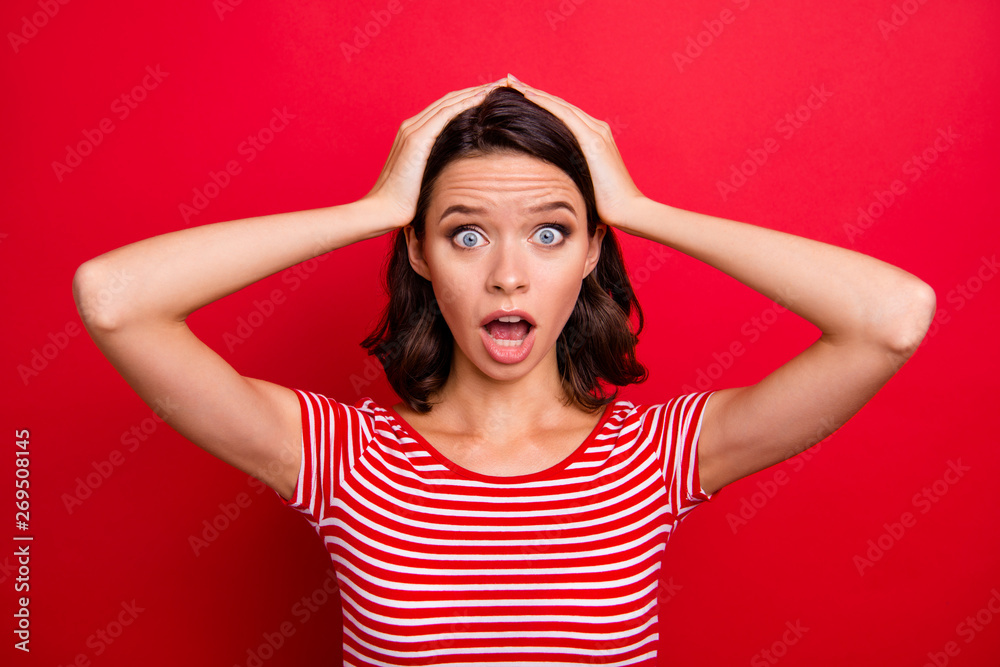 Obraz premium Portrait of disappointed horrified teen teenager astonished impressed wonder horrible terrible news novelty scream shout yell dressed modern clothing isolated bright red background touch hands head