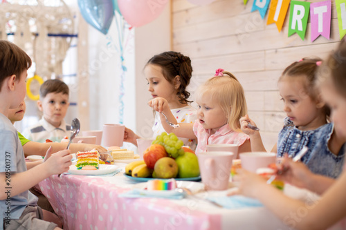 children eat festive cake at birthday party indoor