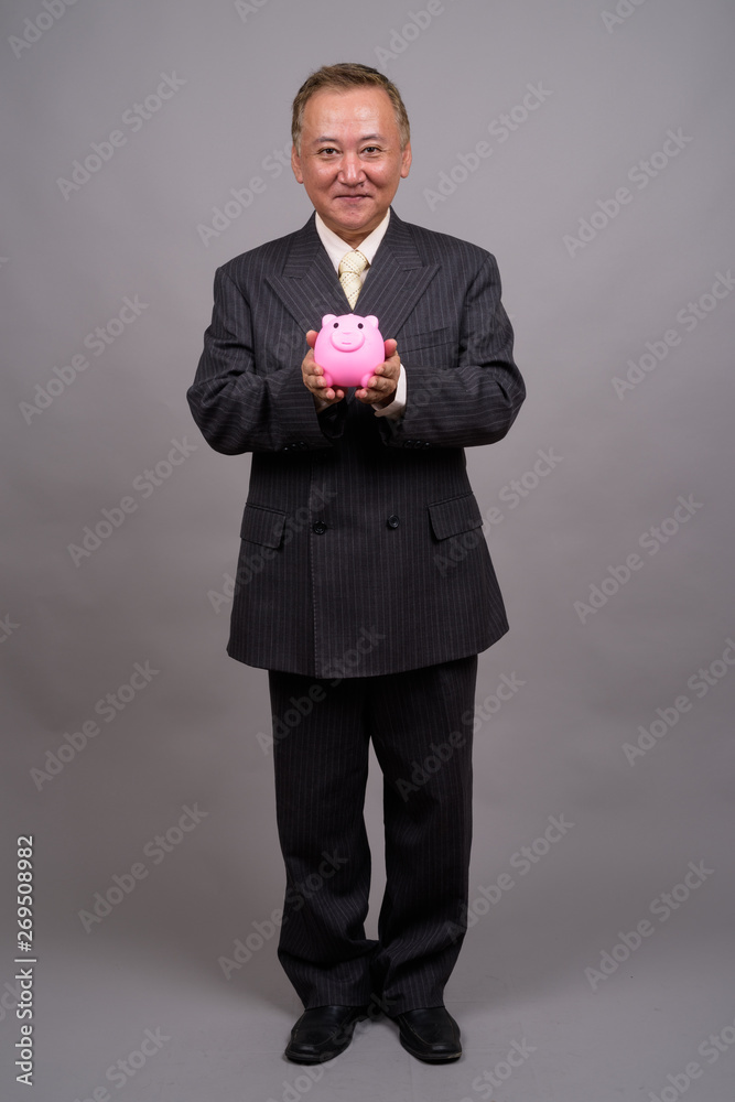 Portrait of mature Asian businessman against gray background Portrait of mature Asian businessman against gray background