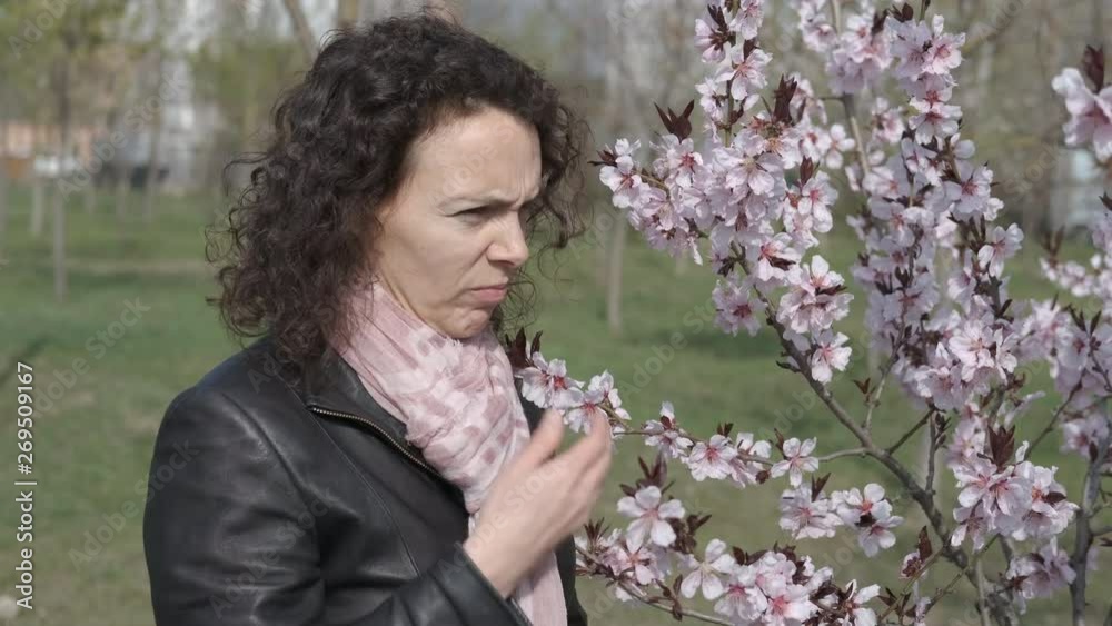 Spring asthma. Pollen allergy. The woman sniffs a flowering tree and an asthma attack begins. Spring asthma. Pollen allergy. The woman sniffs a flowering tree and an asthma attack begins.