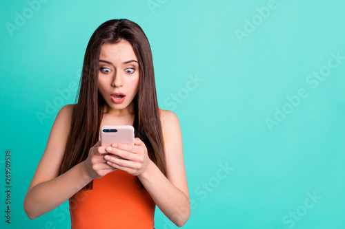 Portrait disappointed frightened lady astonished impressed horrible news text type hold hand device gadget scream unbelievable unexpected anxious mistake orange youth clothes isolated teal background