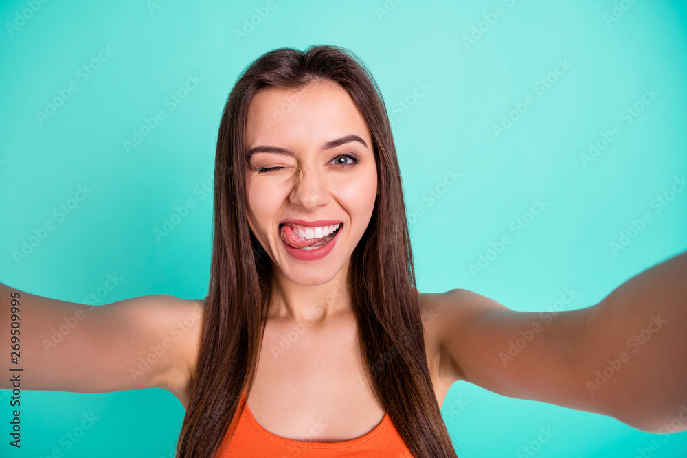 Close up photo beautiful amazing her she lady make take selfies tell speak say skype tongue out mouth blink one eye flirty wear casual orange tank-top isolated bright blue teal turquoise background Close up photo beautiful amazing her she lady make take selfies tell speak say skype tongue out mouth blink one eye flirty wear casual orange tank-top isolated bright blue teal turquoise background
