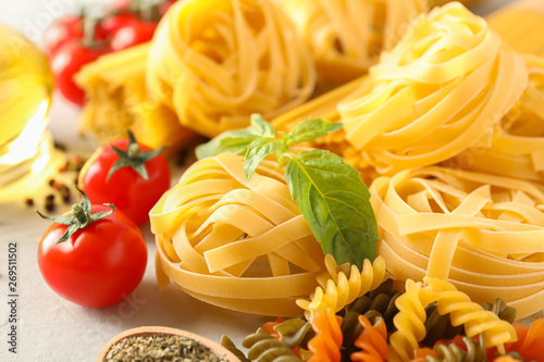 Composition with pasta, tomatoes, spices and olive oil on white background, closeup