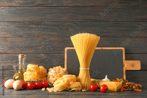 Composition with pasta cooking ingredients on wooden table, space for text