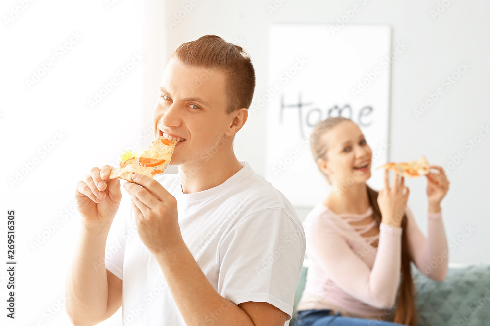 Handsome man eating tasty pizza at home Handsome man eating tasty pizza at home