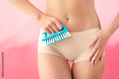 Beautiful young woman with cleaning brush on color background. Depilation concept