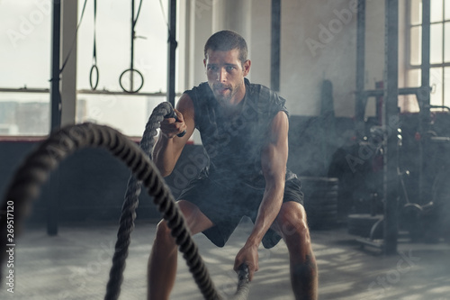 Young man exercising using battle rope