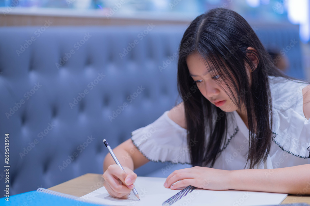 Portrait of young asian female student holding pencil writing on paper answer sheet. Portrait of young asian female student holding pencil writing on paper answer sheet.