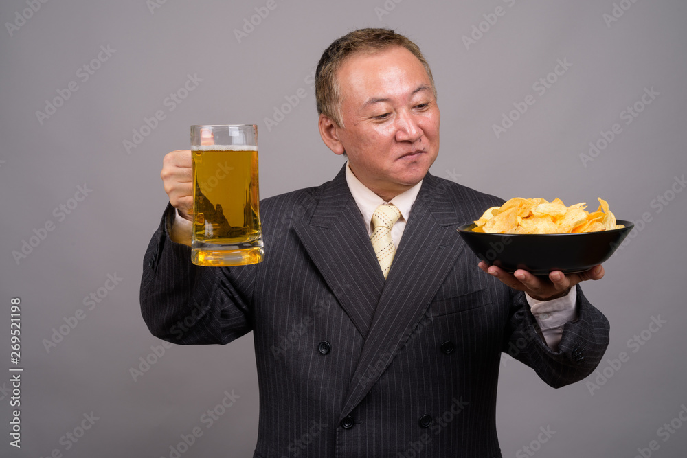 Portrait of mature Asian businessman against gray background Portrait of mature Asian businessman against gray background