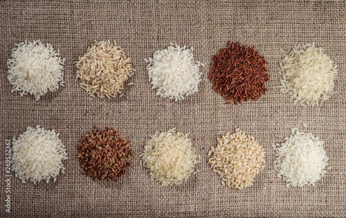 Ten heaps of rice of different varieties on the background of sackcloth. photo