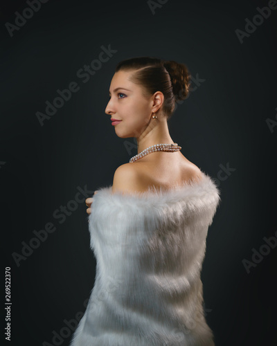 Rich lifestyle. Beautiful sexual woman wearing jewelery and white fur vest. Beauty, fashion.