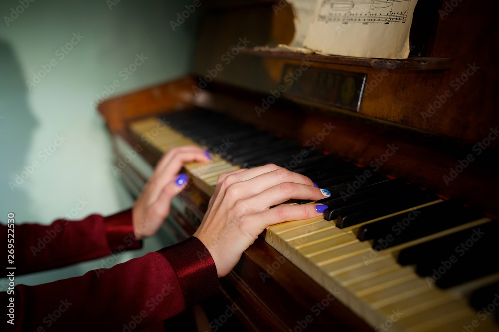 Hands of the girl on the keys of a musical instrument piano.