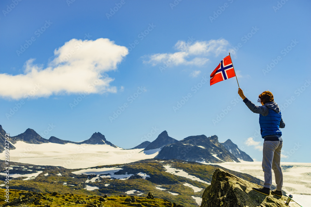 Obraz premium Tourist with norwegian flag in mountains