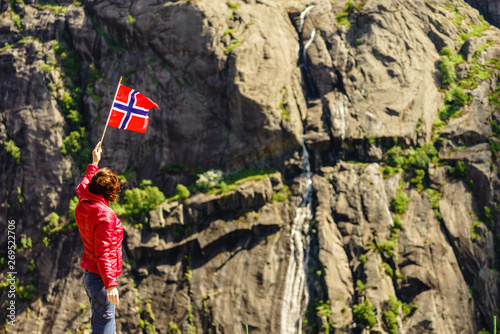 Tourist woman with norwegian flag in rocks mountains