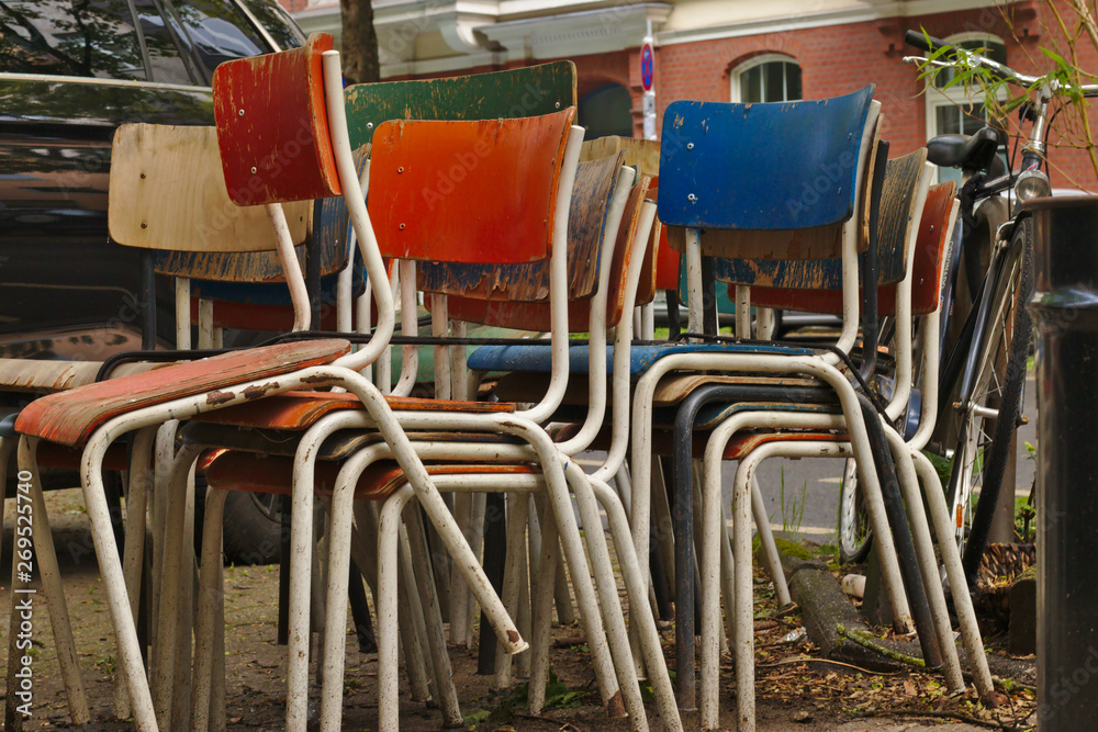 Some old weathered chairs stacked and left on the street