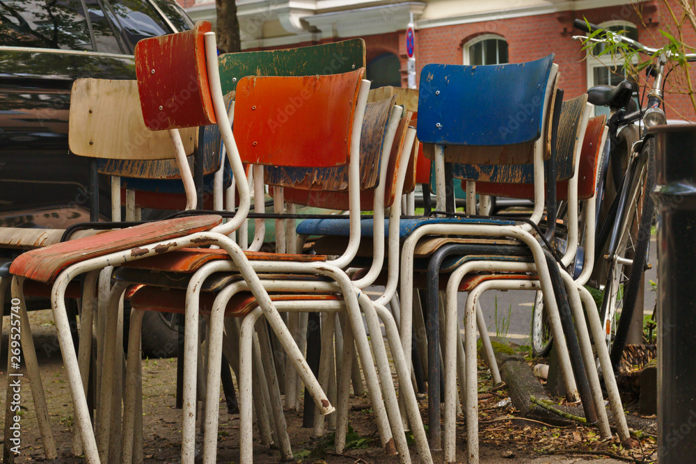 Some old weathered chairs stacked and left on the street Some old weathered chairs stacked and left on the street