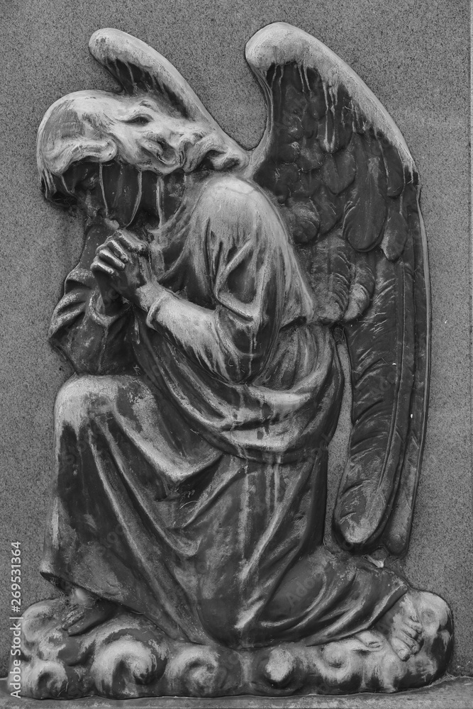 An old and very weathered relief of a praying angel with spread wings on a cemetery in Toronto-Canada.  