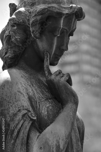 A weathered statue of a thoughtful angel on a cemetery in Toronto-Canada.