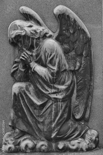 An old and very weathered relief of a praying angel with spread wings on a cemetery in Toronto-Canada. 