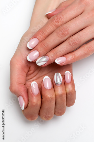 Wedding manicure 2019. White French manicure on long oval nails with silver glitter triangles on the nameless nails against a white background.