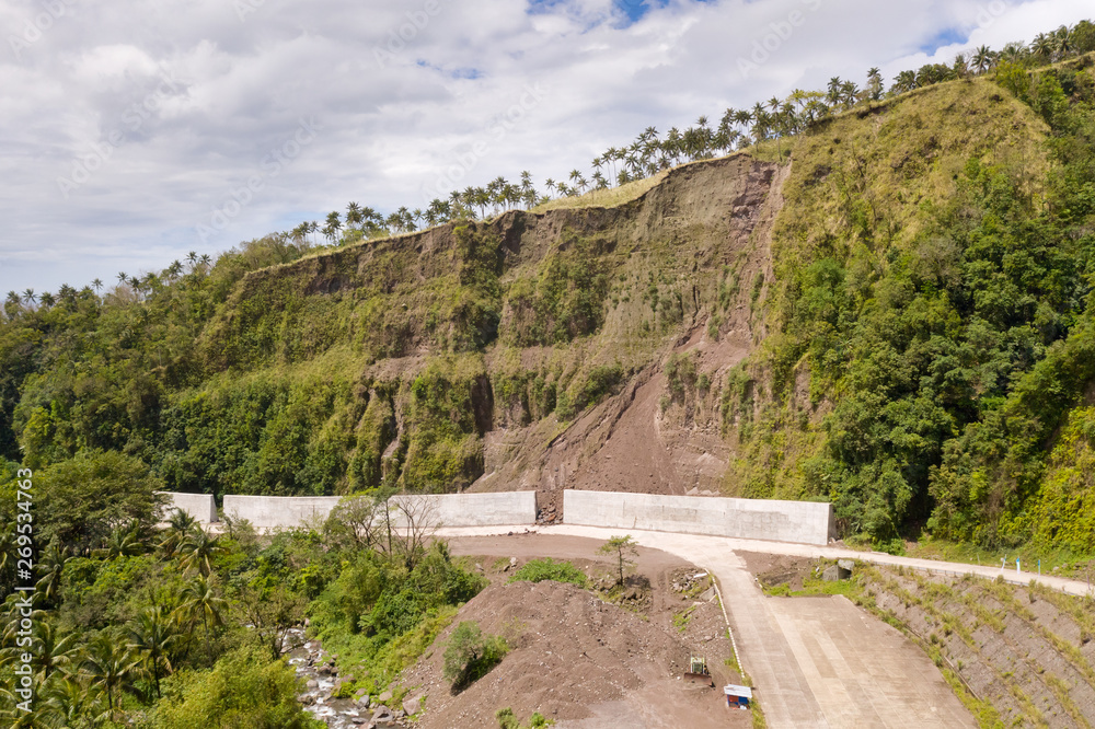 Road with concrete fences on Camiguin Island, Philippines. Protection of the road from rockfalls and landslides. The collapse of the soil on the road in the highlands.