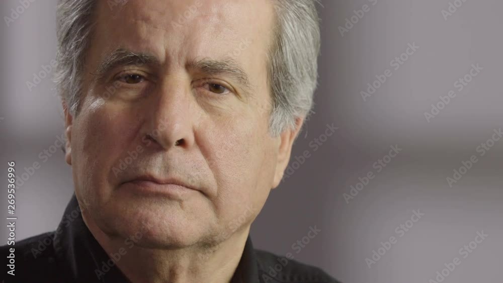 Portrait of a senior aged man, looking at camera and slowly smiling Portrait of a senior aged man, looking at camera and slowly smiling