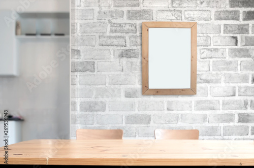 Wooden table top with white brick wall and picture frame background. Copy space for porduct display or montage. photo