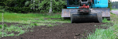 Excavator with shovel has leveled soil to the ground. Panorama view with copy space.