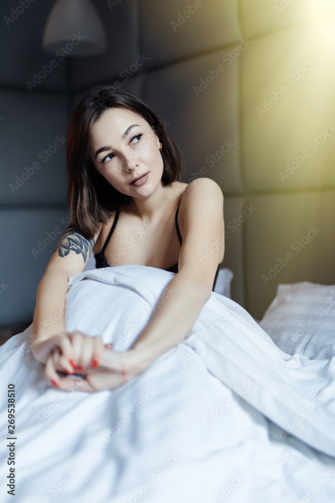 Beautiful young smiling woman sitting on bed in the morning at bedroom. Beautiful young smiling woman sitting on bed in the morning at bedroom.