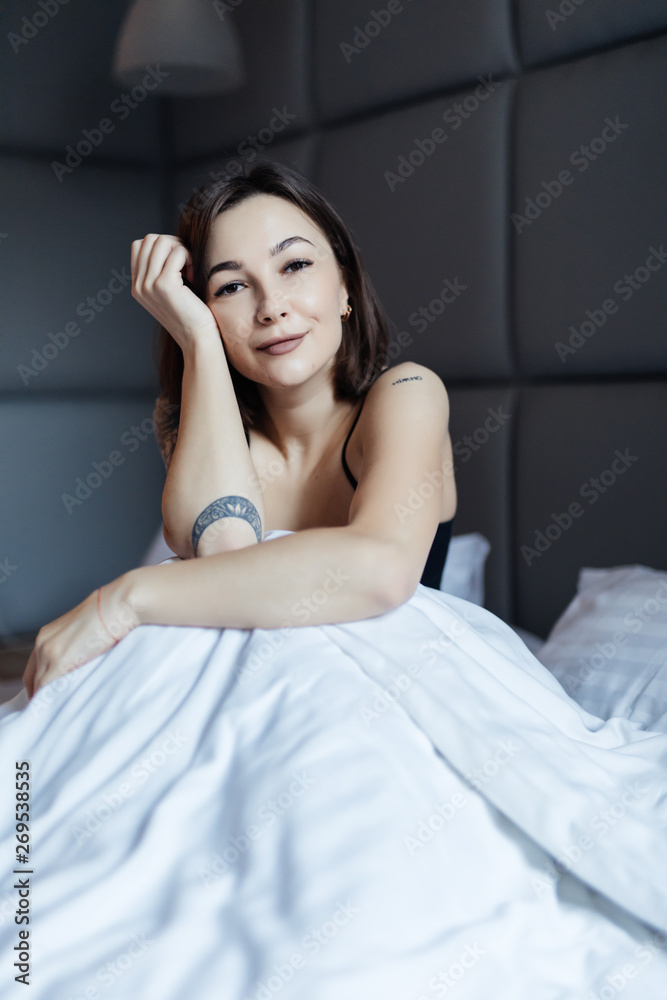 Beautiful young smiling woman sitting on bed in the morning at bedroom. Beautiful young smiling woman sitting on bed in the morning at bedroom.