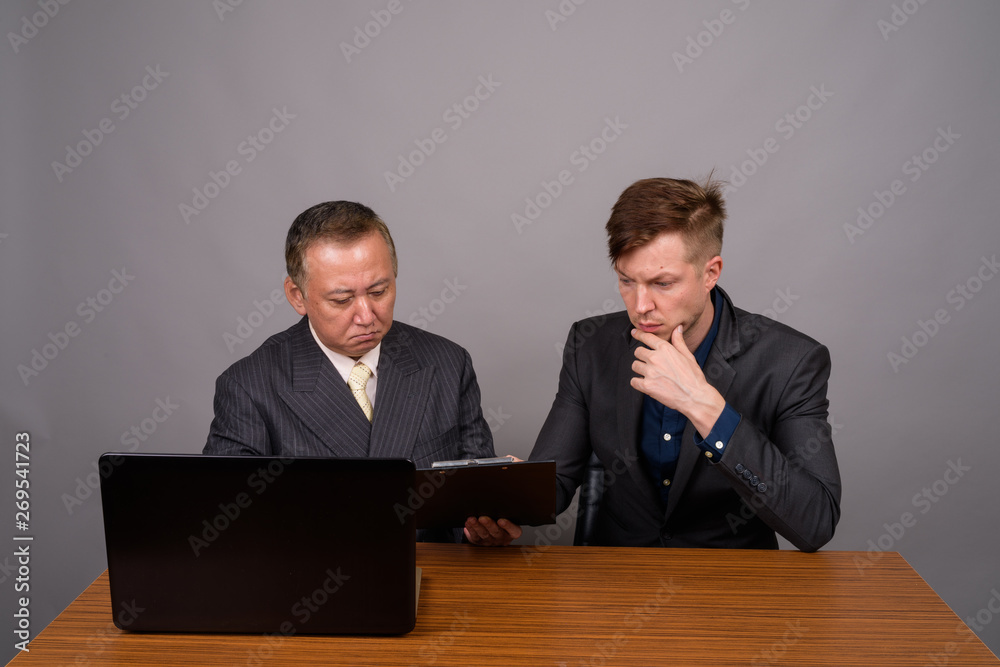 Mature Asian businessman and young Scandinavian businessman agai Mature Asian businessman and young Scandinavian businessman agai