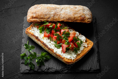 wholegraine ciabatta sandwich with sliced tomatoes, goat cheese, parsley. top view