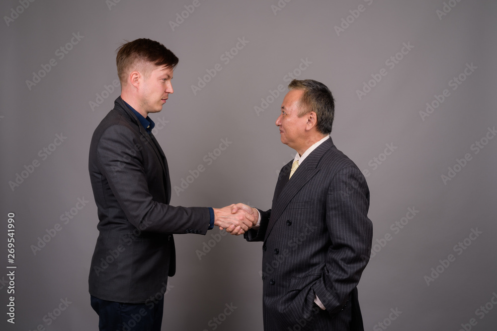Mature Asian businessman and young Scandinavian businessman agai Mature Asian businessman and young Scandinavian businessman agai