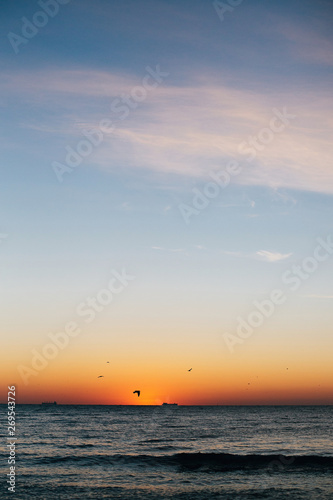 Beautiful sun rise and seagulls flying in red sky above sea waves on tropical island. Waves in ocean at sunset light. Tranquil calm moment. Summer vacation. Copy space © sonyachny