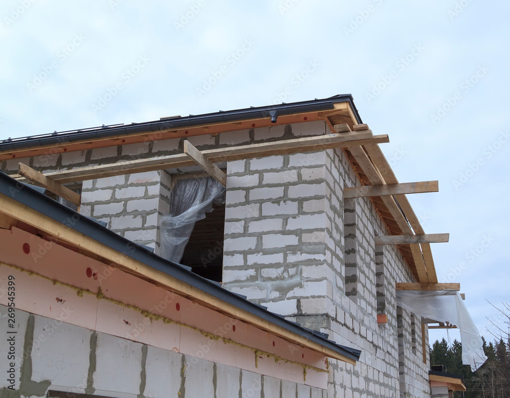 close up view of scaffolding and house under construction with grey folding roof on waterproofing layer
