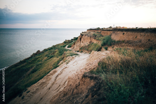 Beautiful sandy cliff  and calm sea surface, pink sky at sunset light. Beach  on tropical island at ocean bay or lagoon. Tranquil calm moment. Summer vacation. Copy space © sonyachny