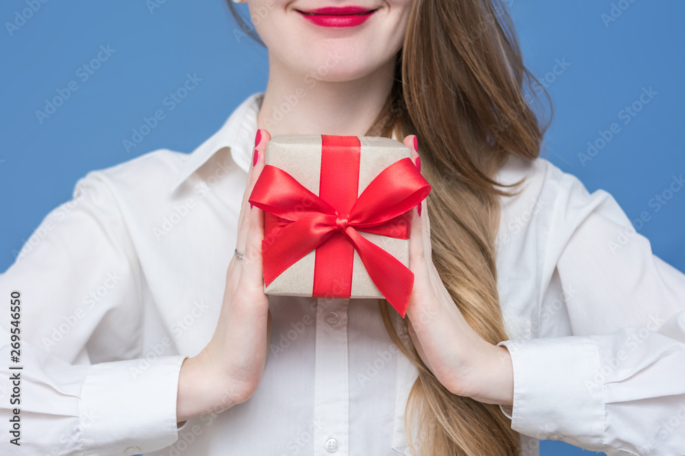 Woman in white shirt holding a box with a gift with a red ribbon, front view, close up Woman in white shirt holding a box with a gift with a red ribbon, front view, close up